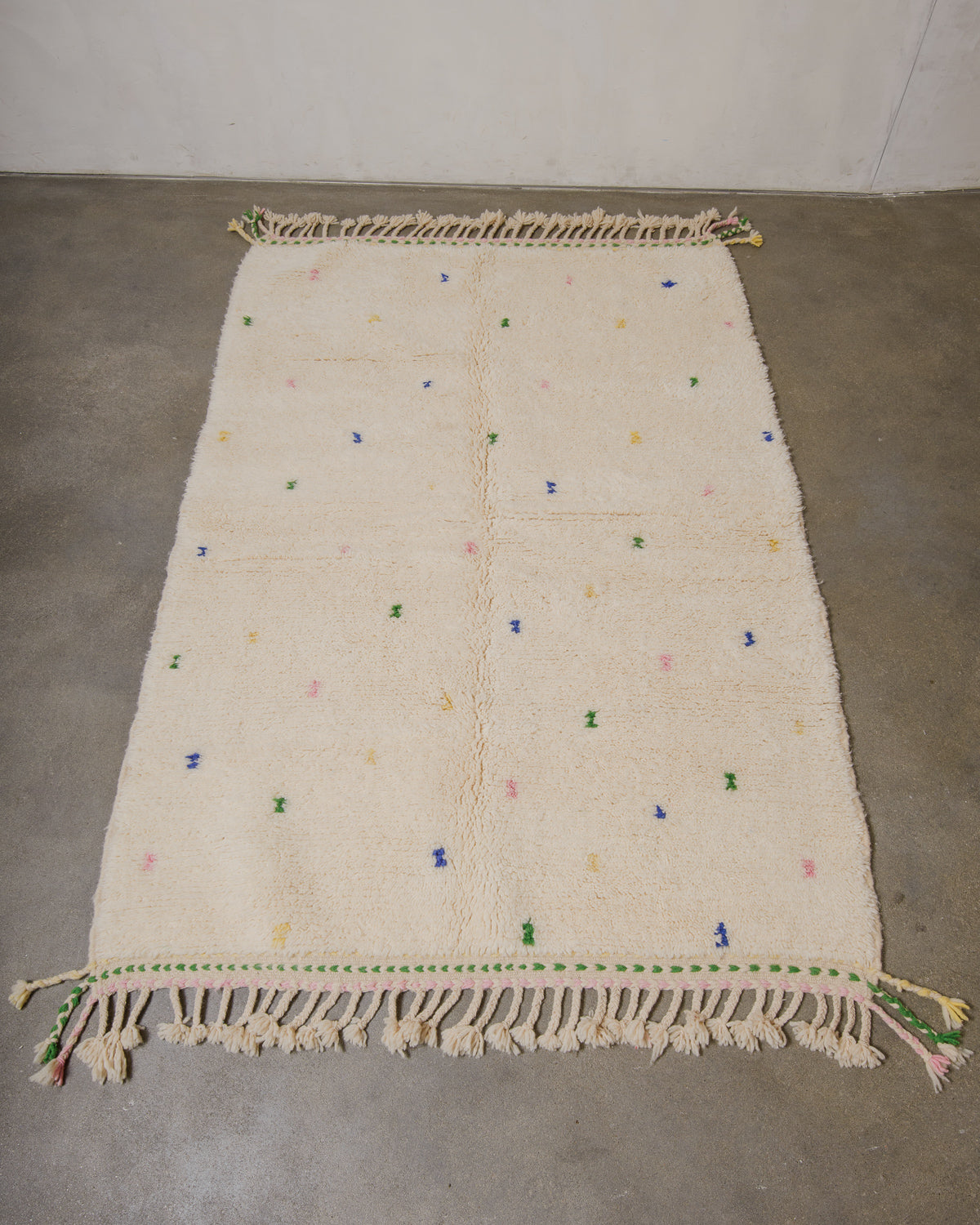 Beige rug with colorful accents on a concrete floor